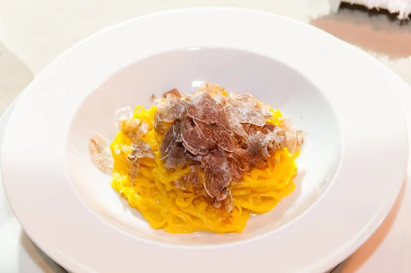 İtalya, Alba 'dan gelen beyaz trüf mantarı bir tabak yumurta makarna tagliolini-spagetti ile dilimlenmiş. 