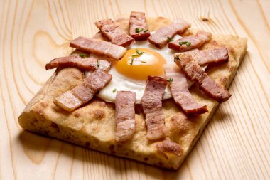 Genova Focaccia dilimi, yumurta ve pastırma ile ahşap kesim tahtası.