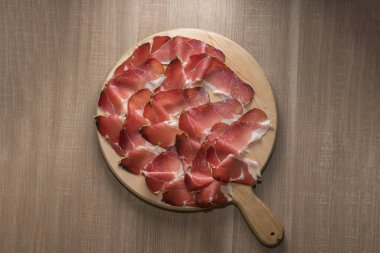 Speck, Güney Tyrol 'dan tipik tütsülenmiş jambon, İtalya' dan Alto Adige - tahta kesme tahtasındaki dilimler.