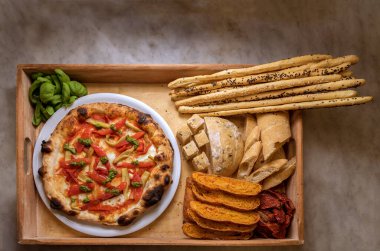 Biberli pizza ve kırsal ahşap tepside ekmek ve ekmek çubukları. Karbonhidrat açısından zengin gıdalar. Üst görünüm