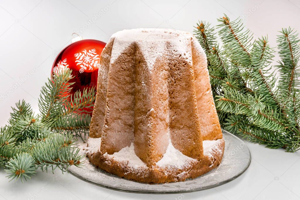 Pandoro, traditional Italian Christmas cake, with icing sugar between fir branches and Christmas ball, isolated on white