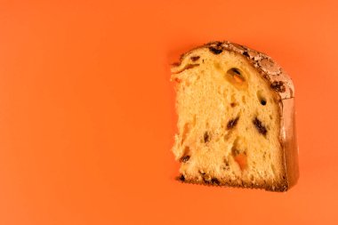Panettone, Milan 'dan klasik Noel pastası, turuncu arka planda izole edilmiş bir dilim.