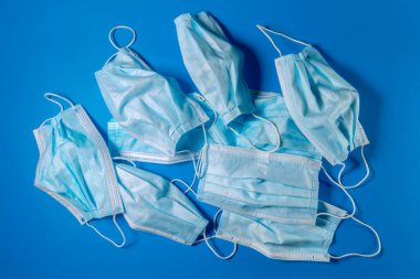 Mavi arka planda cerrahi yüz maskeleri kullanılıyor. Covid-19 korunması için tıbbi maskeler - ekolojik geri dönüşüm kavramı