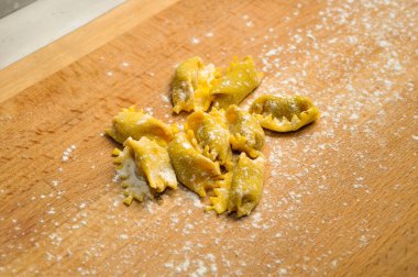 Ravioli del plin, tipik Langhe, Piedmont, İtalya makarnası. Tahta kesme tahtasında taze çiğ agnolotti yapıldı.