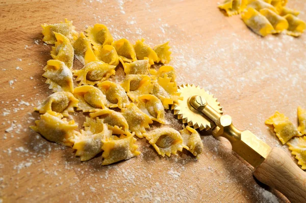 Ravioli del plin, Langhe, Piedmont, İtalya 'dan tipik makarna. Tahta kesme tahtasının üzerinde tekerlekli bıçakla agnolotti.