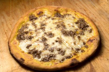 Eritilmiş peynir ve ahşap kesim tahtasının üzerinde et soslu körili pizza.