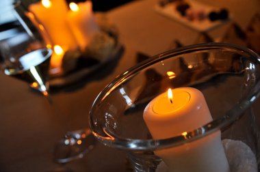 Cam kavanozda mum yakarken diğer mumlar arka planda odak dışı.