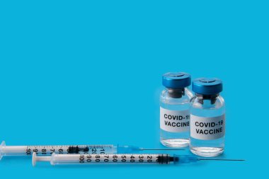Coronavirus COVID-19 aşısı. Mavi arkaplanda izole edilmiş şırınga şişeleri, kopyalama alanı ile konsept bileşimi