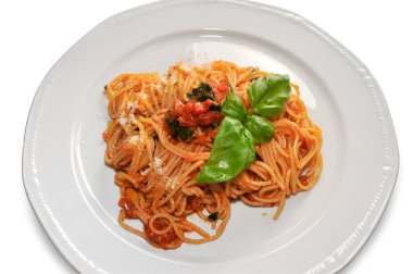 Beyaz tabaktaki fesleğen yapraklı domates soslu spagetti, üst manzara, kapat.