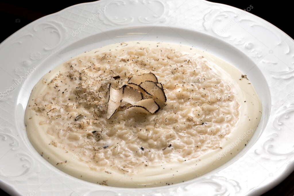 Creamy cheese risotto with slices of truffle, in white dish, close up