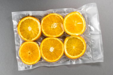 Gri arka planda izole edilmiş turuncu dilimler vakumlanmış.