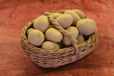 Tahta bir masanın üzerinde eski bir hasat sepetinde taze patates.