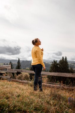 Dağların arkasında tek başına duran güzel bir kızın portresi. Güzel gökyüzü, güzel doğa