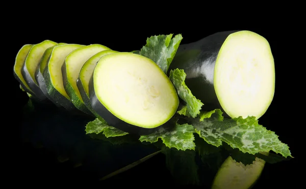 Zucchine tagliate a fette e foglie su nero — Foto Stock