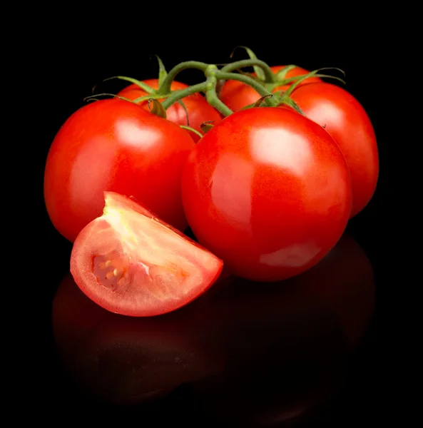 Tomatoes green twig with sliced halves on black — Stock Photo, Image