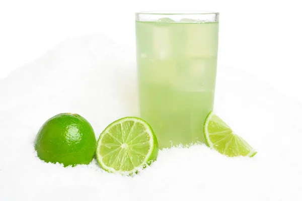 Glass of lime juice with ice cubes,limes on snow on white — Stock Photo, Image