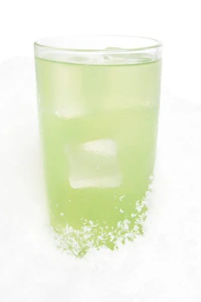 Glass of lime juice with ice cubes on snow on white — Stock Photo, Image