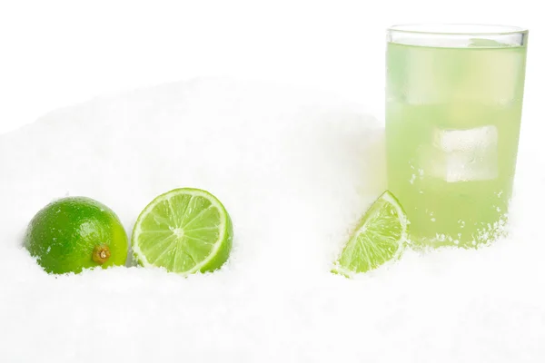 Glass of lime juice with ice cubes,limes on snow on white — Stock Photo, Image