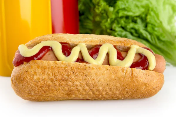 Hotdog com ketchup e mostarda com salada no fundo — Fotografia de Stock