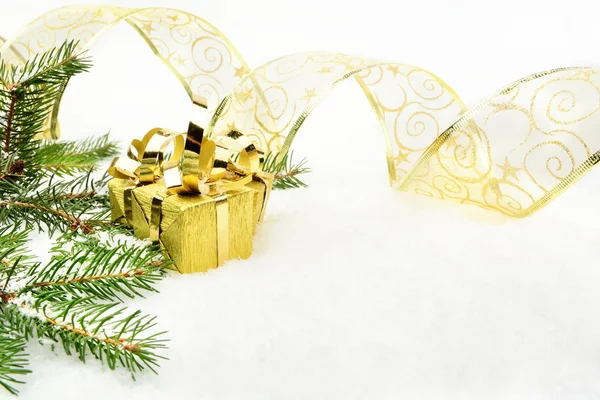 Gold julklappar med guld band och nålar fir på snö — Stockfoto
