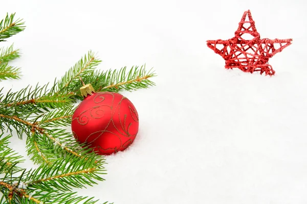 Red christmas baubles with red star and needles fir on snow — Stock Photo, Image