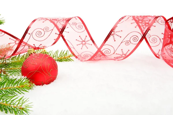 Röd christmas småsak och nålar fir och band på snö — Stockfoto