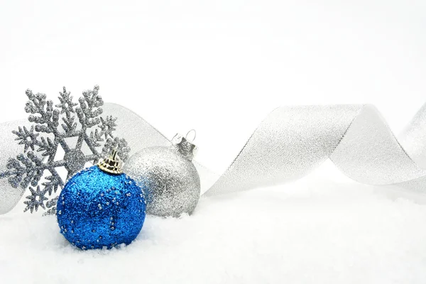 Zilveren en blauw glinsterende kerstballen met lint op sneeuw — Stockfoto