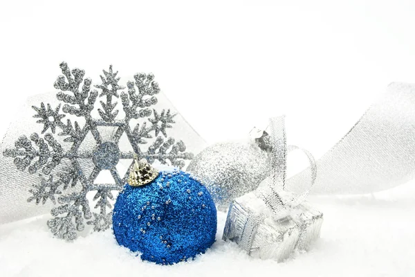 Silver and blue christmas glittering baubles with ribbon on snow — Stock Photo, Image