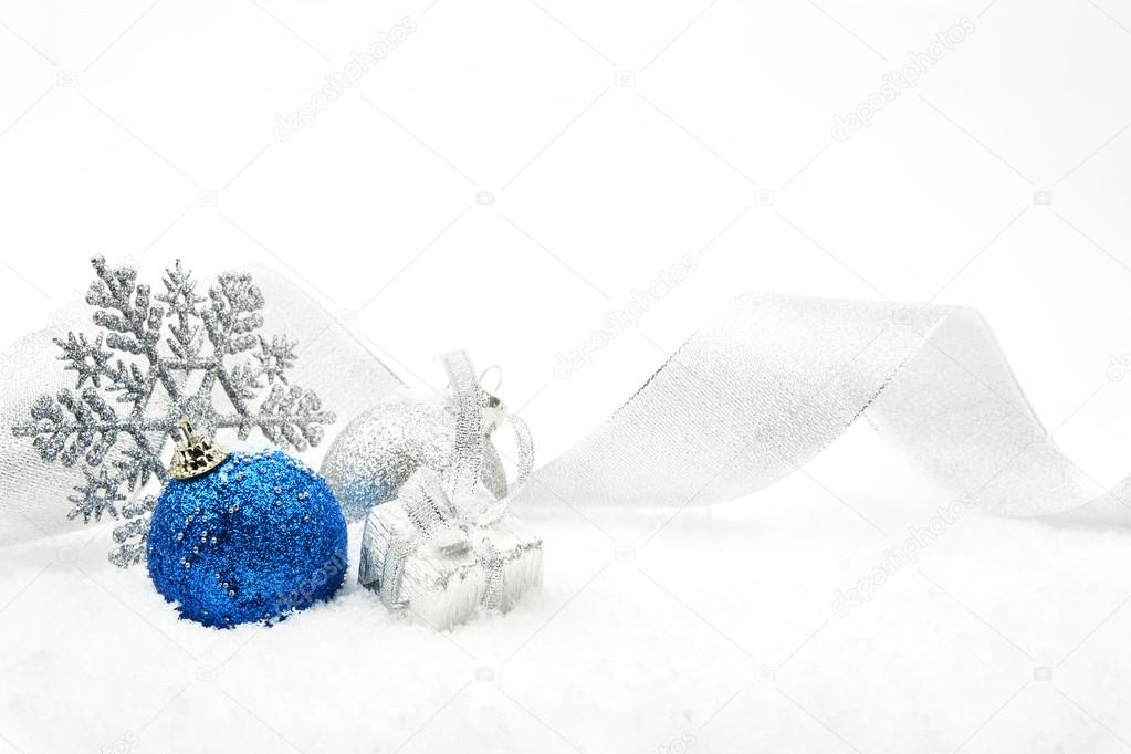 Silver and blue christmas glittering baubles with ribbon on snow