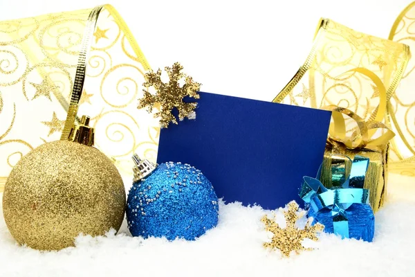 Goldene und blaue Weihnachtsdekoration auf Schnee mit Wunschkarte — Stockfoto