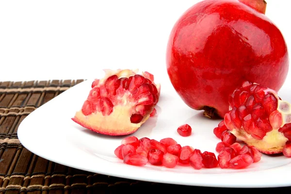 Studio shot open pomegranate on plate wooden mate — Stock Photo, Image