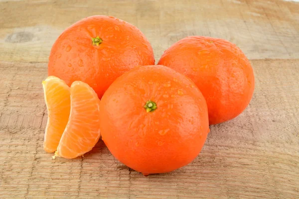 Mandarines with pieces isolated on wooden table — Stock Photo, Image