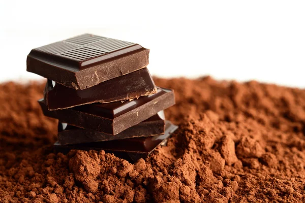 Heap of blocks of chocolate on cocoa powder — Stock Photo, Image