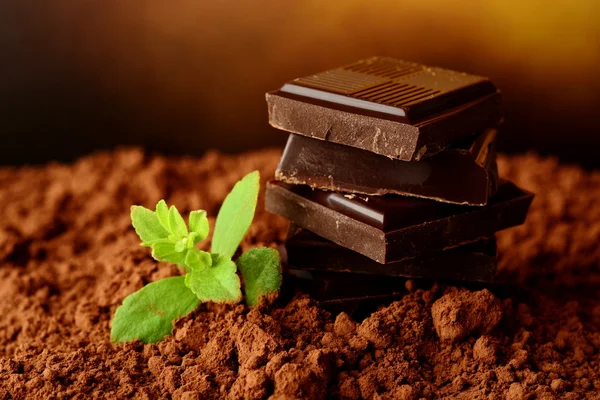 Heap of blocks of chocolate on cocoa powder — Stock Photo, Image