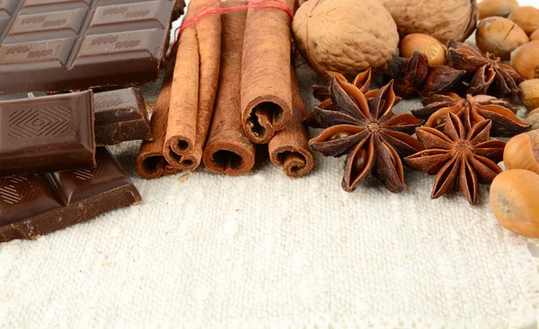 Romantic set of chocolate,anise,nuts and cinnamon on white flax — Stock Photo, Image