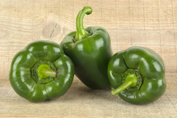 Studio shot of green bell peppers on wooden plank — Stock Photo, Image