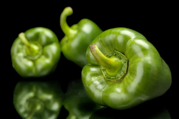 Gruppe grüner Paprika in der Ecke isoliert auf schwarz — Stockfoto