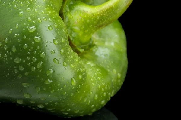 Skåret skud af grøn peberfrugt isoleret på sort med vanddråber - Stock-foto