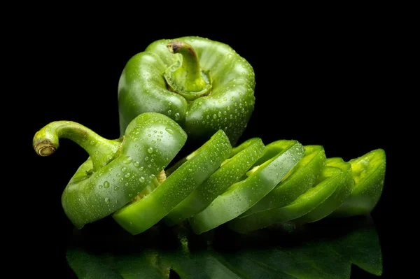 Closeup segmenten van groene paprika op zwart met druppels wate — Stockfoto