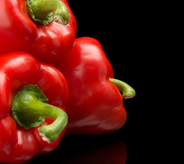 Group of red bell peppers in the corner isolated on black — Stock Photo, Image