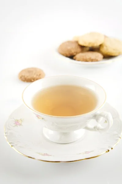 Old-style studio shot of cups of tea with cookies on white — Stock Photo, Image