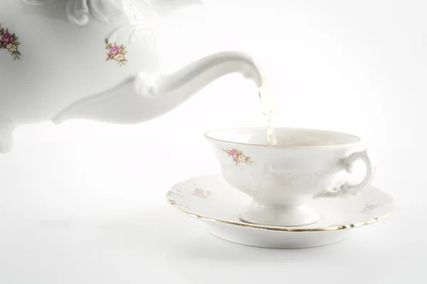 Viejo estilo verter té a taza sobre fondo blanco — Foto de Stock