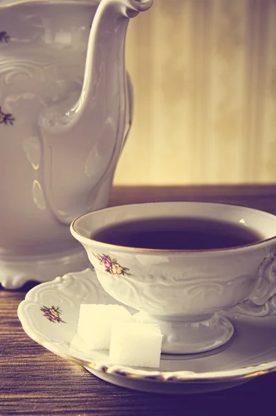 Old-fashioned vintage jug with tea with wallpaper background