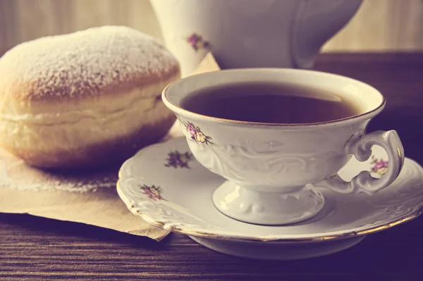 Primo piano colpo di ciambella con tazza di tè sul tavolo in vecchio stile — Foto Stock