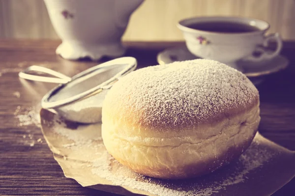 Closeup shot of donut with cup of tea on table in old-fashioned — Stock Photo, Image