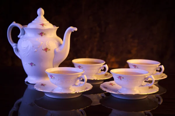 Kettle with four cups of tea on black background — Stock Photo, Image