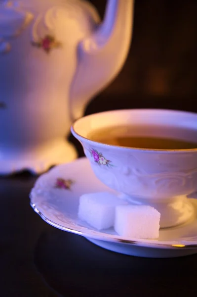 Old-style kettle with cup of tea on black — Stock Photo, Image