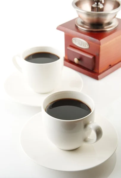 Cups of coffee with saucer and mill on white — Stock Photo, Image