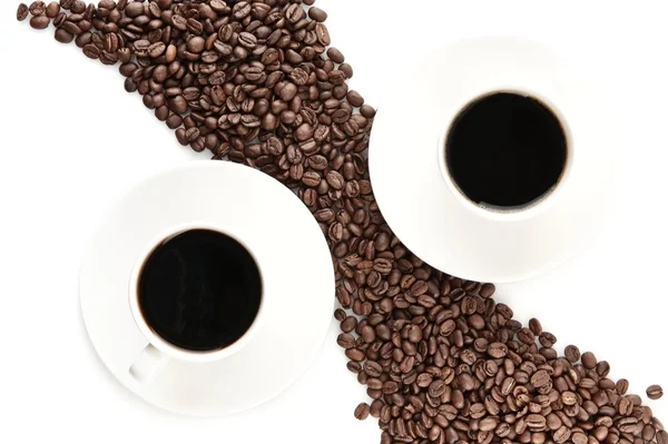 Grãos de café dispostos na diagonal com xícaras de café em branco — Fotografia de Stock