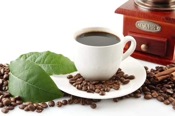 Scattered coffee beans with cups of coffee and leaf — Stock Photo, Image